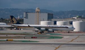 Singapore Airlines plane on runway with cityscape in background.